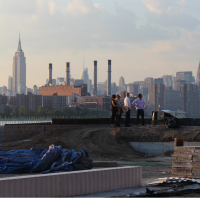 A wide shot of real estate experts evaluating a site, with the skyline in the background